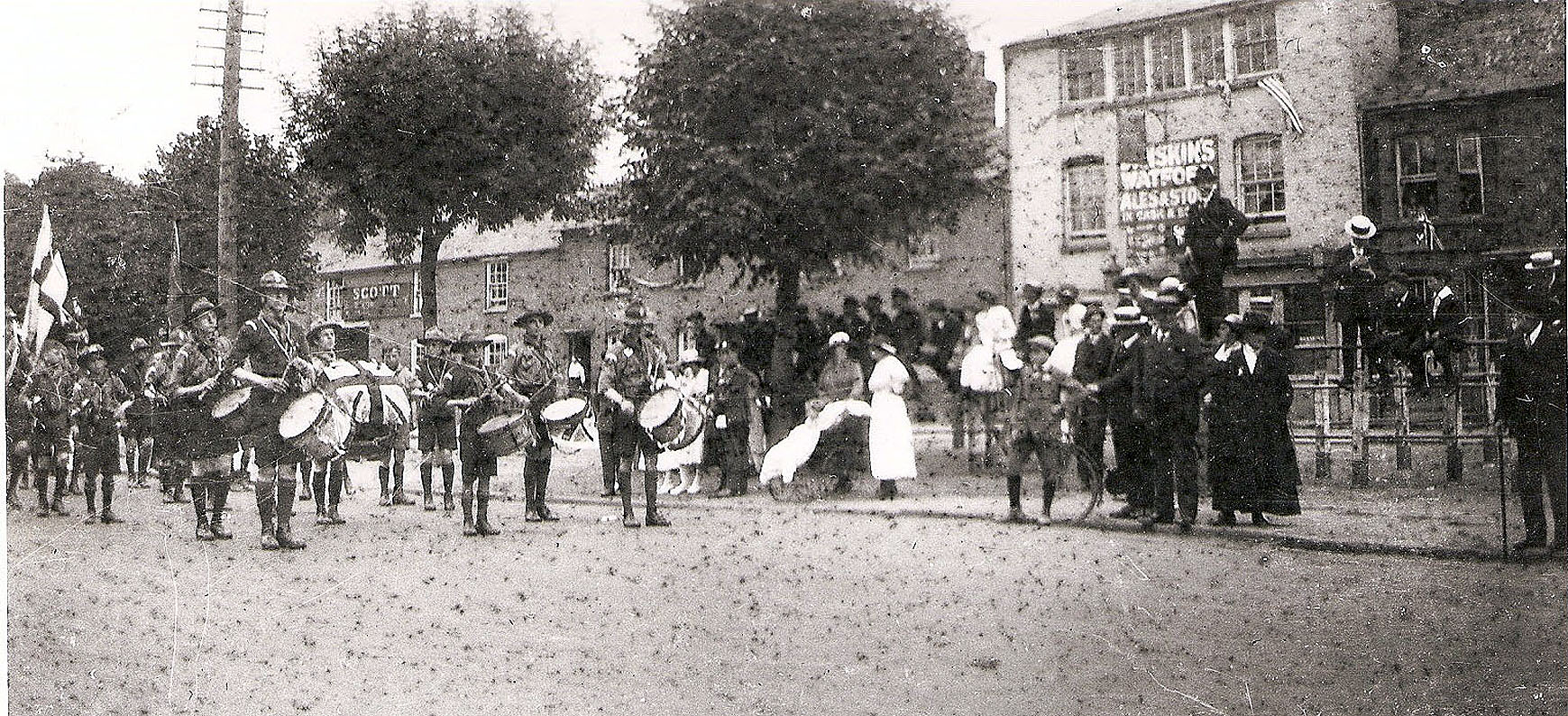 A photo much degraded showing a few people milling about in the square looking in direction of the camera.